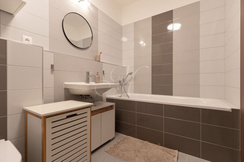 A bathroom with a bathtub and white tiles in a 2-room apartment, modern furnishings.