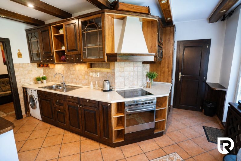 A kitchen in a 2-room apartment with dark wooden furniture and built-in appliances.