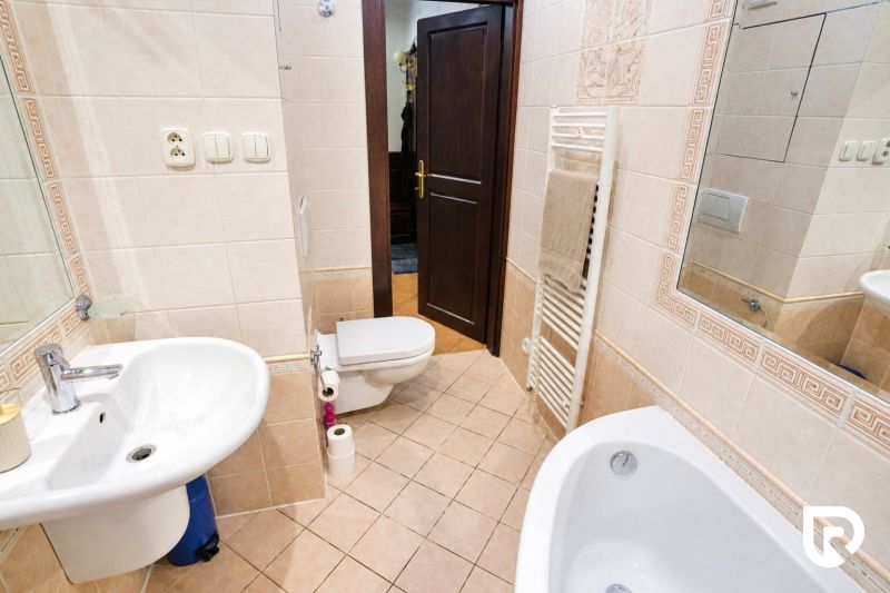 A bathroom with a bathtub, sink, and toilet in a 2-room apartment with ceramic tiles.
