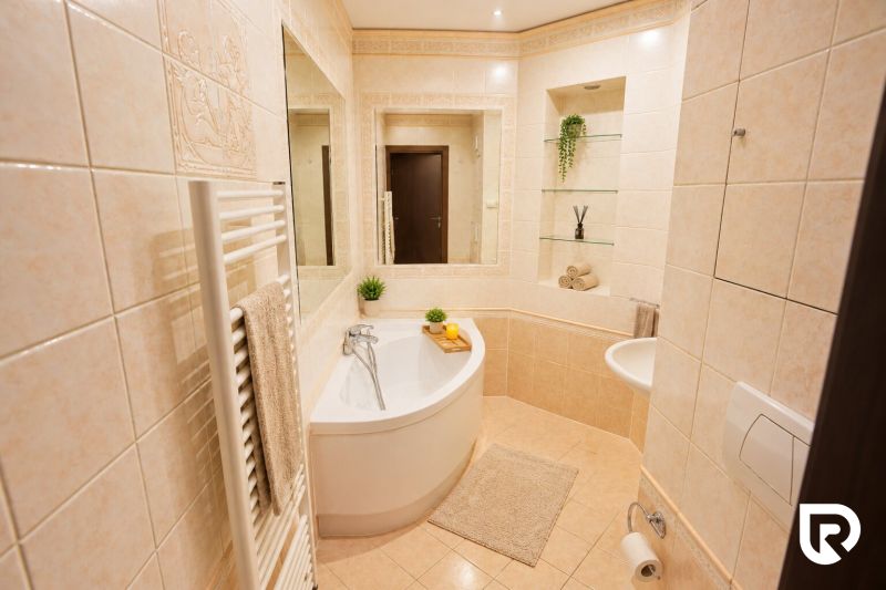 A bathroom with a bathtub and tiles in a 2-room apartment.