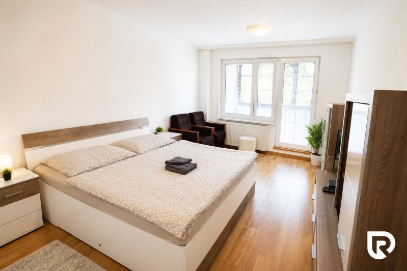 A bedroom with a large bed and a wooden decor floor in a two-room apartment.