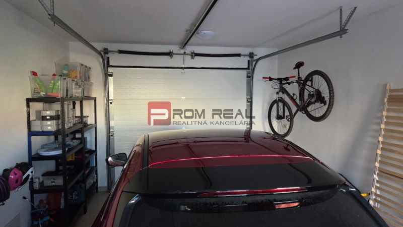 A family house garage with shelves, a bicycle, and a car.