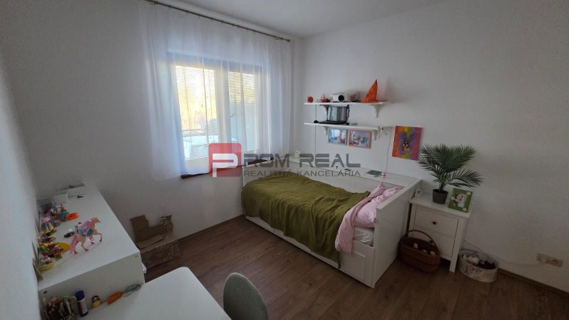 Children's room in a family house with a bed, a desk, and a wooden decor floor.