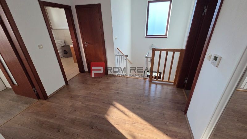 A hallway in a family house with a wooden decor floor and a staircase.