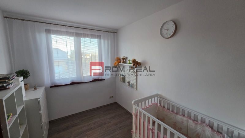 Children's room with a crib, shelf, clock, and floor with wooden decor in a family house.