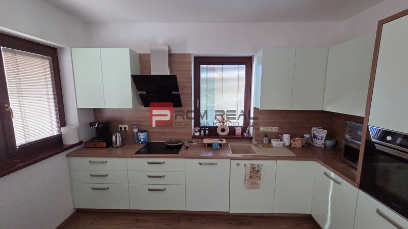 A kitchen in a family house with light cabinets and a wooden decor floor.