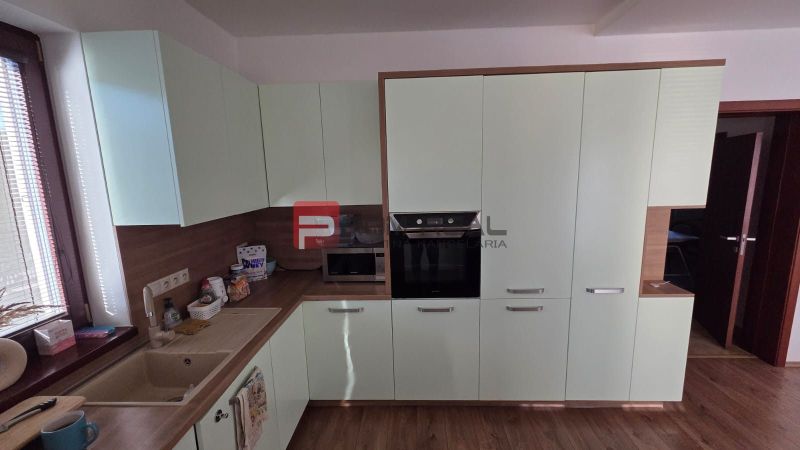 A kitchen in a family house with a wooden decor floor and green cabinets.