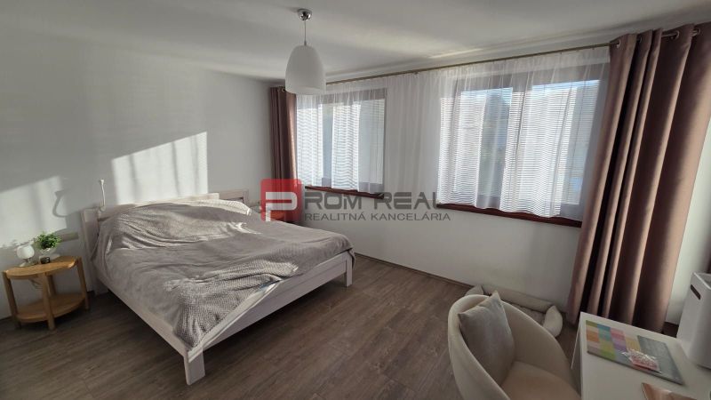 A bedroom in a family house with a bed, a nightstand, and a wooden decor floor.