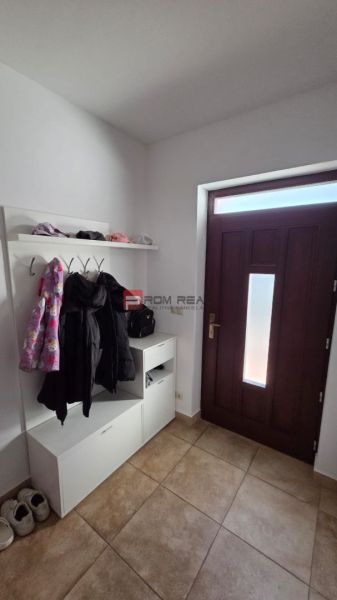 Entrance hallway in a family house with a shoe cabinet, coat hooks, and brown tiles.