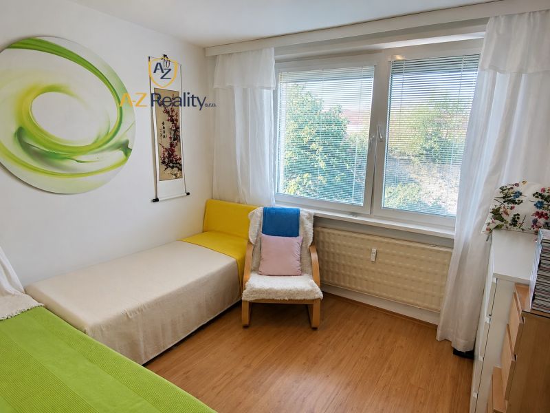 A room in a 4-room apartment with a bed, a chair, and a floor with a wooden decor.