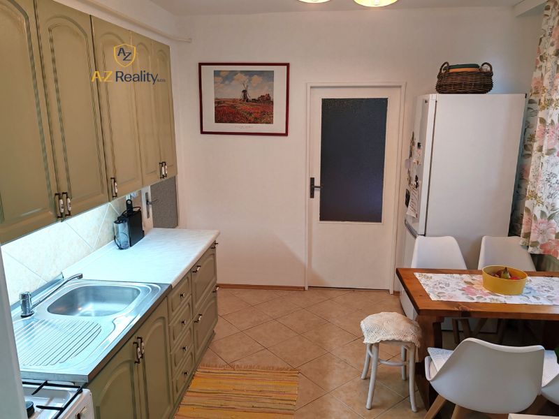 A kitchen in a 4-room apartment with a retro kitchen unit, a dining table, and ceramic flooring.