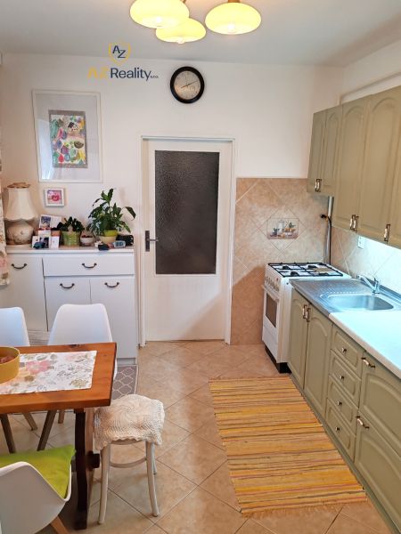 A kitchen with a dining table, white cabinets, and beige tiles in a 4-room apartment.