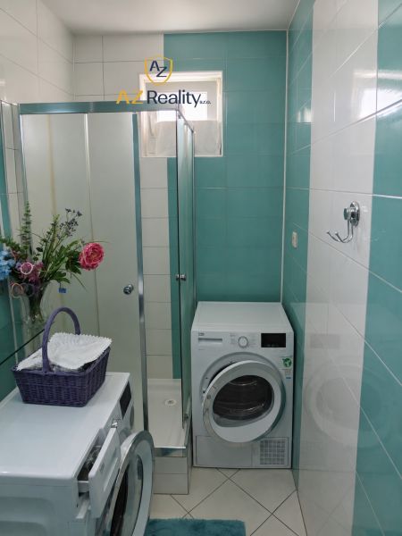 Bathroom with a shower and a washing machine in a 4-room apartment, with blue and white tiles.