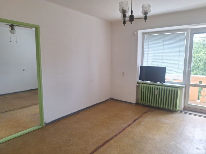 A room in a 2-room apartment with a wooden decor floor and a balcony.