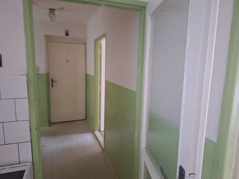 A hallway in a 2-room apartment with white and green walls, simple doors.