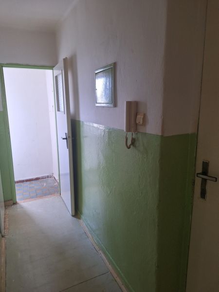A corridor with white and green walls, a door to a room, a phone on the wall.