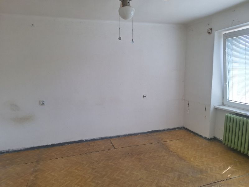 A room with white walls and a floor with a wooden decor in a two-room apartment.