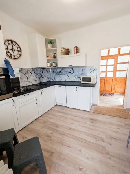 A kitchen in a family house with white cabinets and a wood-patterned floor.