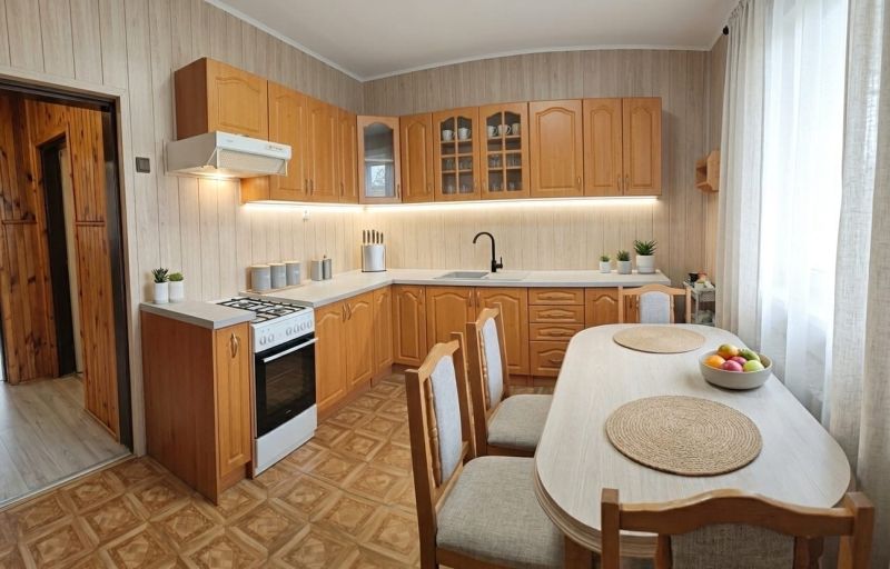 A kitchen in a family house with wooden cabinets and a floor with a wooden decor.