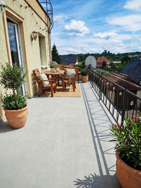 A balcony of a family house in Lakšárska Nová Ves with wooden furniture and flowers in pots.