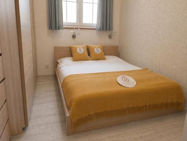 A bedroom in a two-room apartment with a bed and a wooden decor floor.