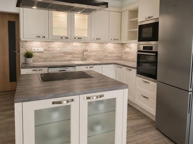A kitchen in a 2-room apartment with a wood-patterned floor and stainless steel appliances.