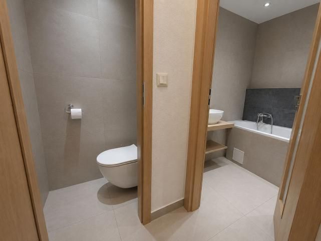 Bathroom and toilet with tiles and a bathtub in a 2-room apartment.