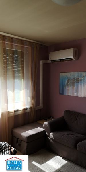 Living room with a dark sofa and air conditioning in a studio apartment.