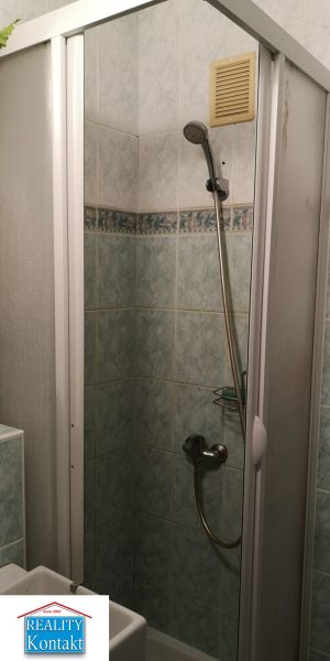 Bathroom with a tiled shower stall and a shower head in a studio apartment.