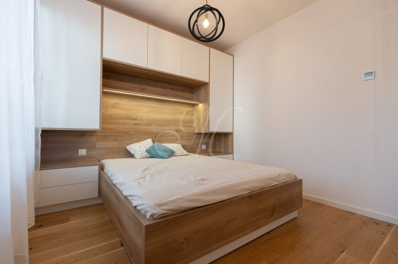 Bedroom in a 2-room apartment with a bed and storage spaces, floor with wood decor.