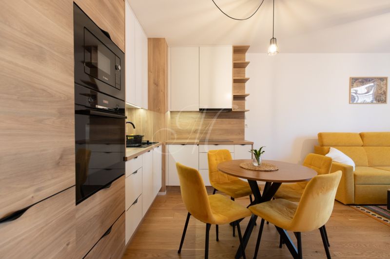 A kitchen in a 2-room apartment with a dining table, yellow chairs, and a wooden decor floor.