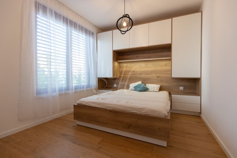 A bedroom with a bed, furniture with a wooden decor, and a large window in a two-room apartment.