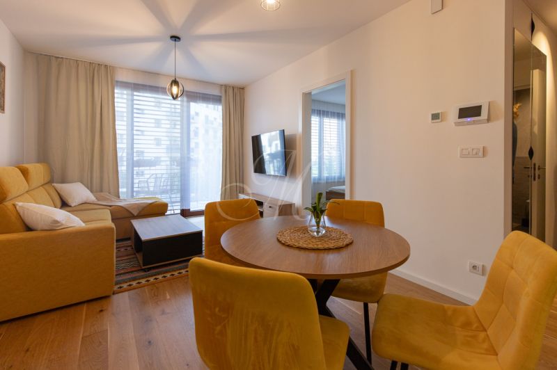 Living room with a sofa, table, and yellow chairs in a two-room apartment, floor with wooden decor.