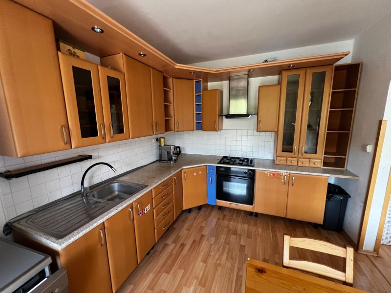A kitchen in a 3-room apartment with a wood-patterned floor and built-in appliances.