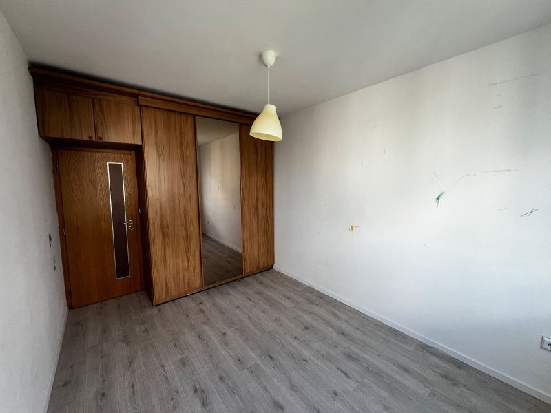 A room in a 3-room apartment with a wooden decor floor and built-in cabinets.