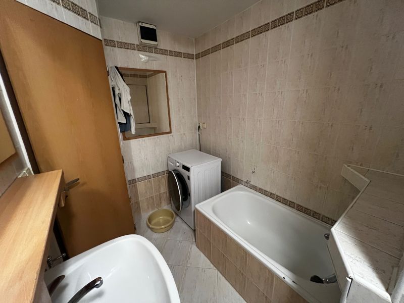 Bathroom with a bathtub, washing machine, and mirror in a 3-room apartment.
