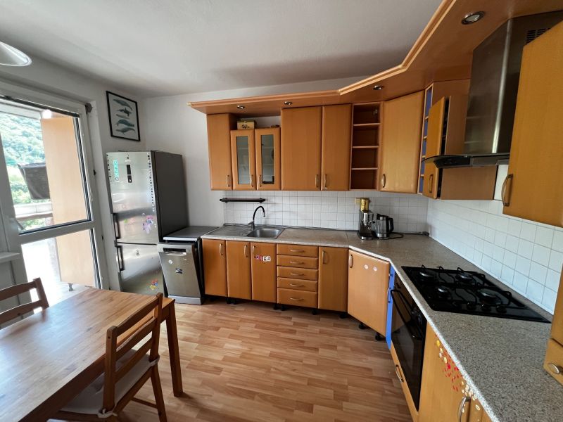 A kitchen in a 3-room apartment with a wooden decor floor and stainless steel appliances.