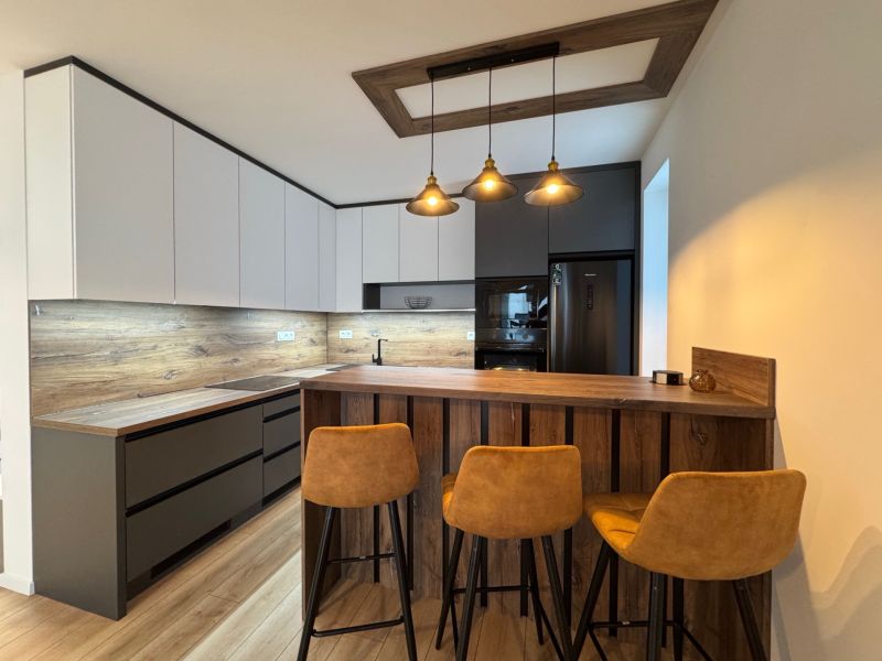 A kitchen in a 2-room apartment with a bar counter and a floor with a wood decor.