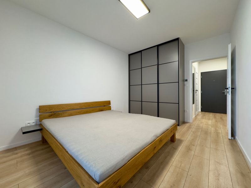Bedroom with a bed and built-in wardrobe, floor with wood decor in a 2-room apartment.