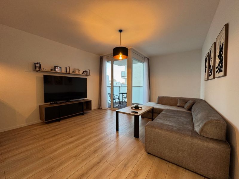 Living room in a two-room apartment with a sofa and a balcony, floor with wood decor.