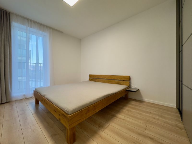 A bedroom in a two-room apartment with a bed and a wooden decor floor.