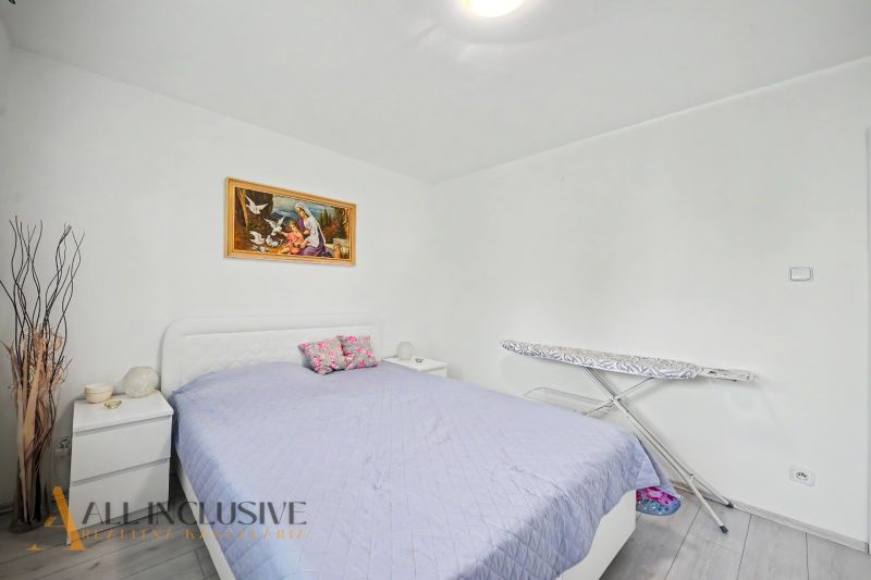Bedroom in a 3-room apartment with a bed, painting, and ironing board.