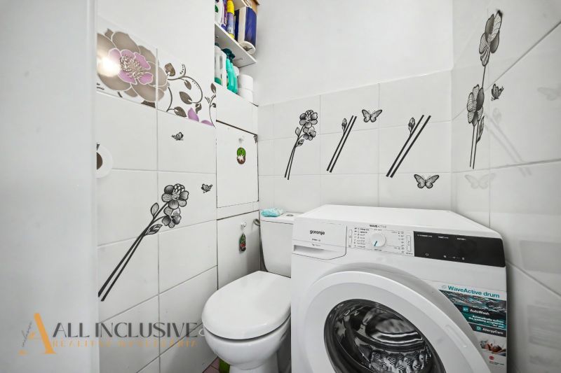 A bathroom in a 3-room apartment with a modern washing machine and decorative tiles with flowers.