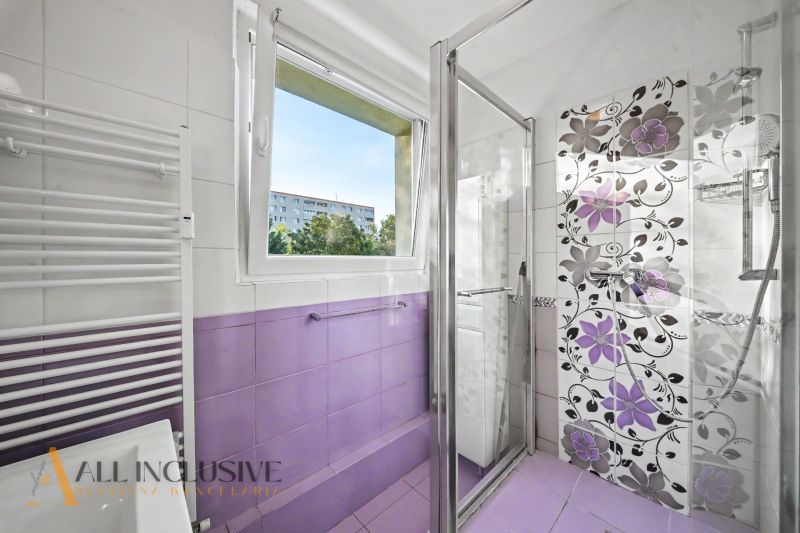 A bathroom in a 3-room apartment with purple tiles and a shower.
