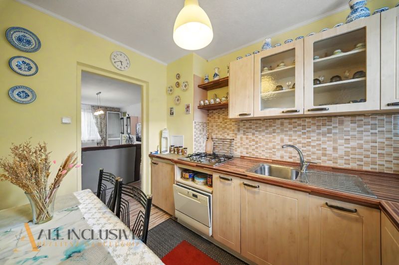 A kitchen in a 3-room apartment with classic cabinets and a dining table with decorative accessories.