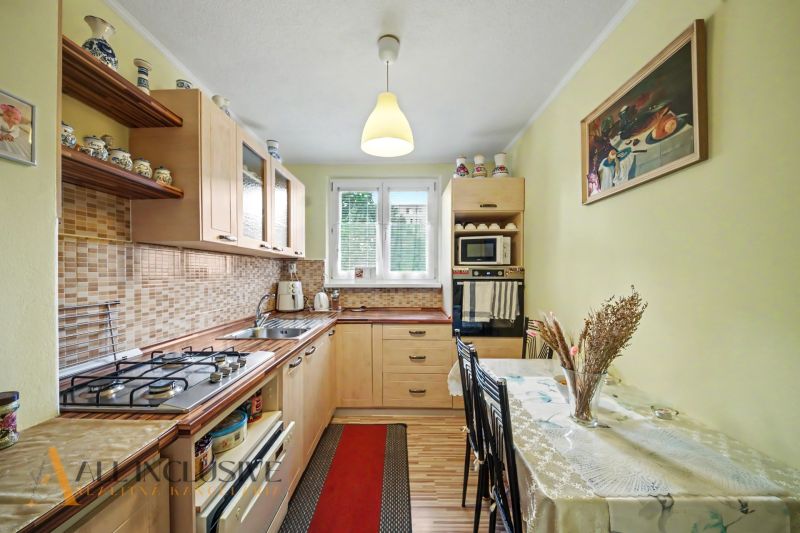 A kitchen in a 3-room apartment with a wooden decor floor and a dining table.