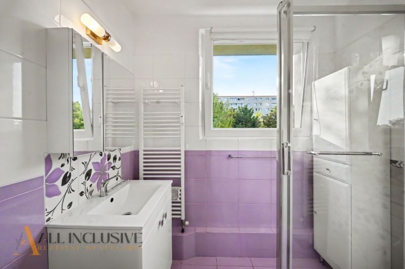 A bathroom in a 3-room apartment with a shower and purple tiles.