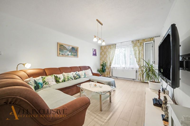 Living room in a 3-room apartment with a comfortable sofa and a television, floor with a wooden decor.