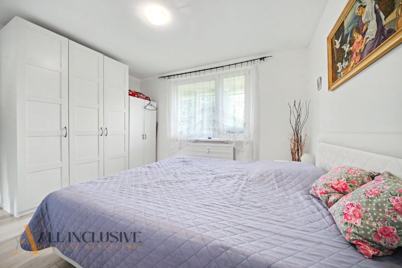 A bright bedroom in a 3-room apartment with white furniture and a decorative painting.