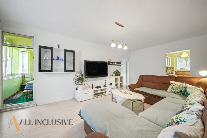 Living room in a 3-room apartment with a large sofa and a television on the wall.